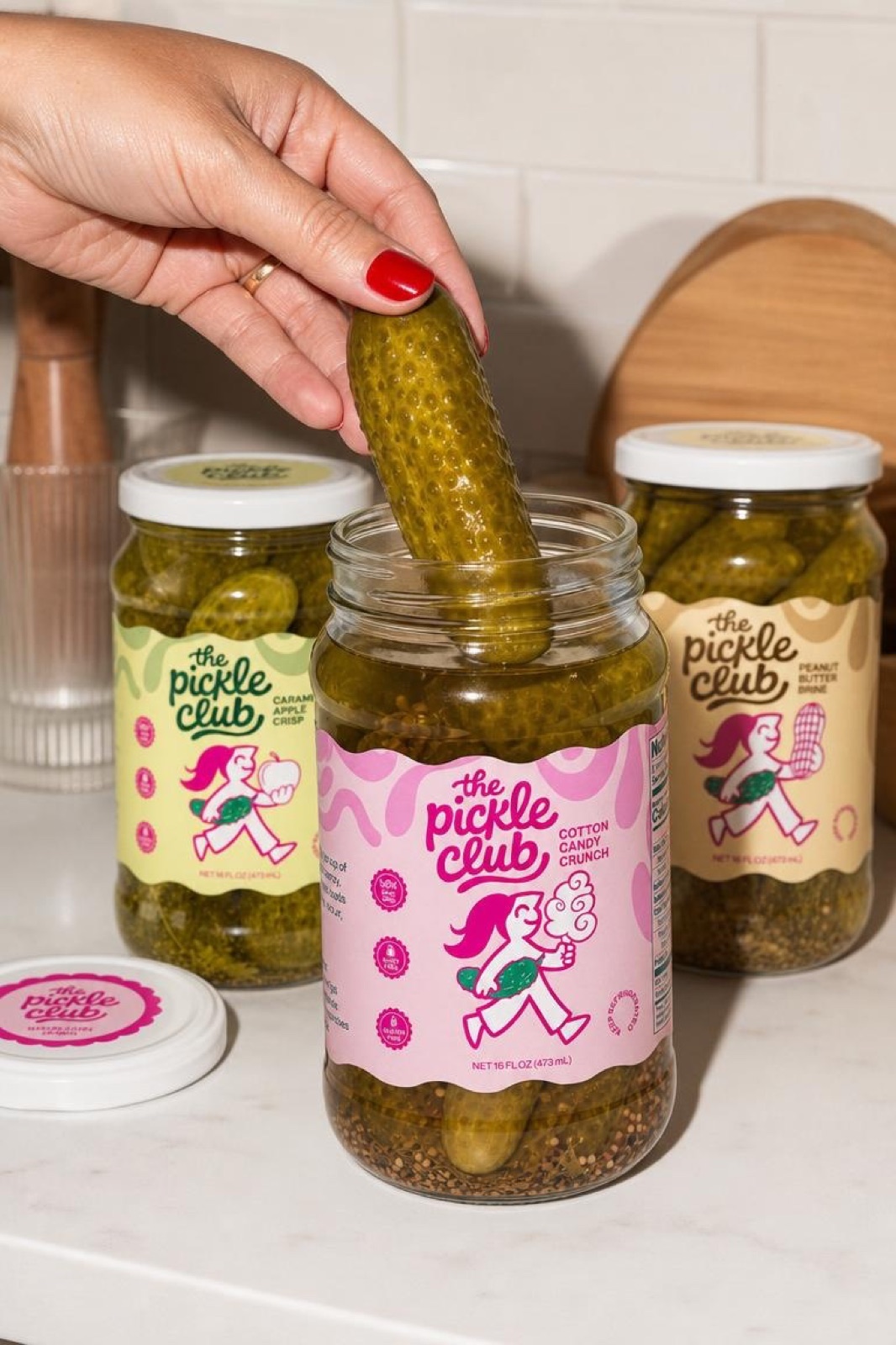 Hand lifting a pickle from the Pickle Club packaging family